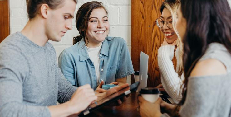 Group of team members sitting around a table and smiling.
